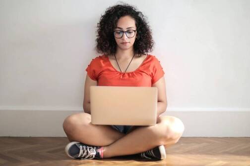 Selbständigkeit und ortsunabhängig arbeiten heisst, auch mal am Boden zu sitzen. Digitale Nomadin arbeitet sitzend am Boden.