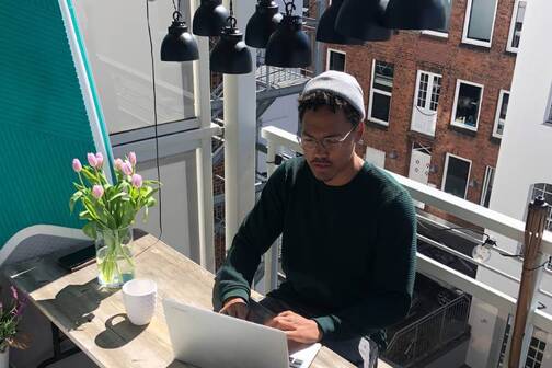 Hast du die Selbstorganisation im Griff, arbeitest du von überall. Ein digitaler Nomade arbeitet auf einer Terrasse.