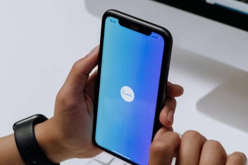 Canva – eine nützliche App für jeden Tag iPhone mit blauem Screen und Canva-App Logo