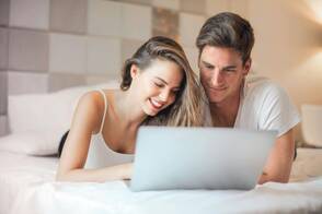 Unterhaltung durch Streaming-Dienste (Foto: Olly / pexels) Ein Paar liegt auf dem Bett und wählt einen Film auf dem Mac