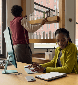 Personne assise à un bureau dans un salon de coiffure en train de travailler sur un iMac.